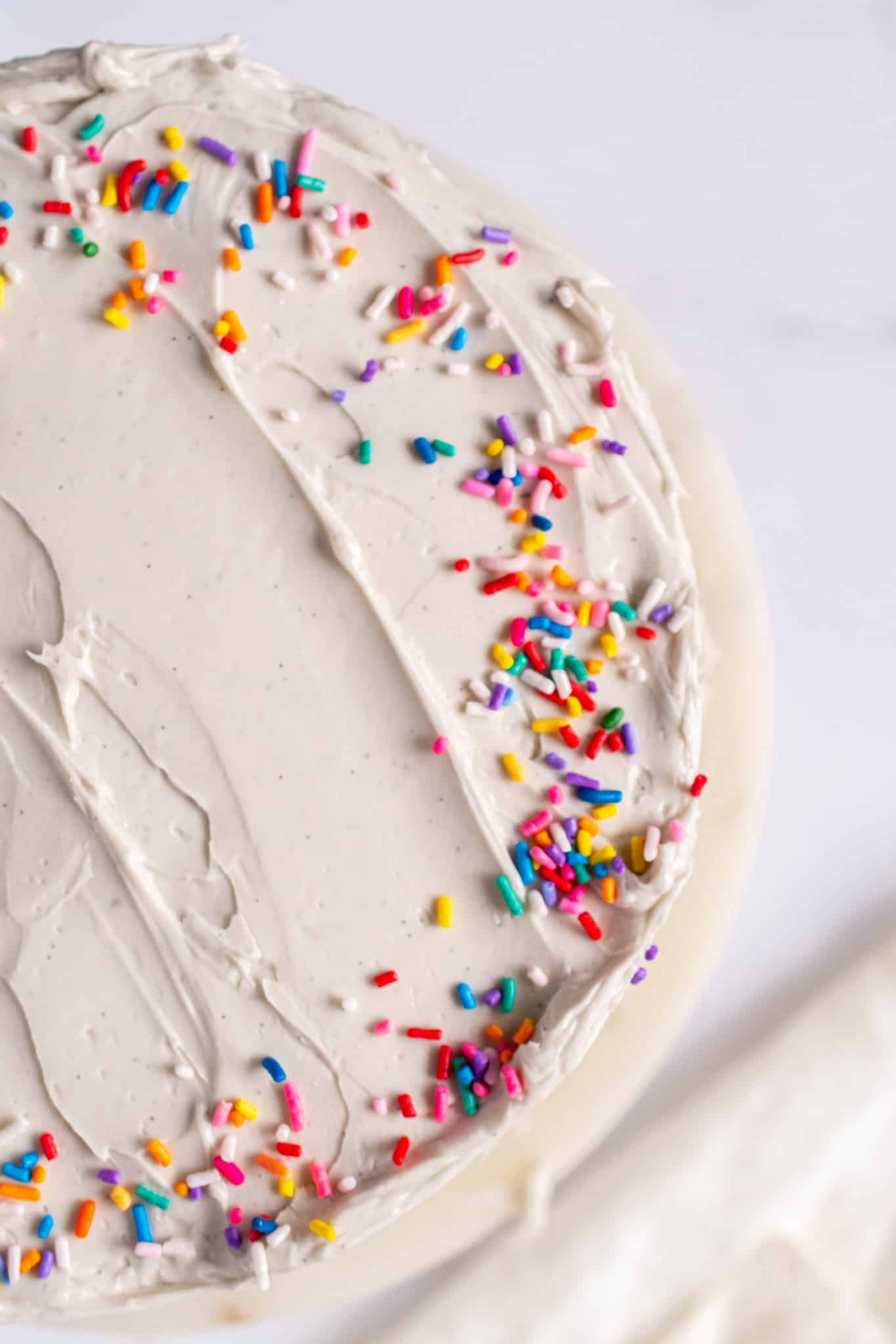 Overhead shot of a cake frosted with buttercream and topped with rainbow sprinkles.