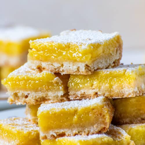 Close up stack of homemade lemon bars with silky yellow lemon filling and buttery shortbread crust dusted with powdered sugar