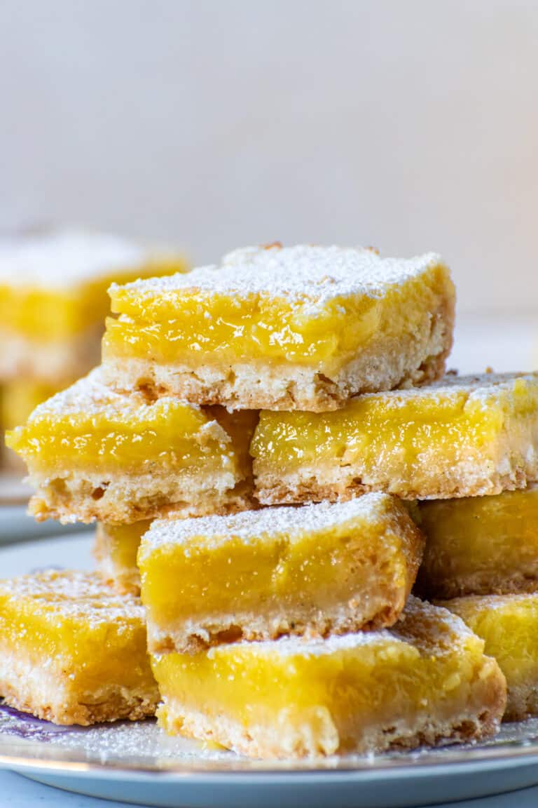 Close up stack of homemade lemon bars with silky yellow lemon filling and buttery shortbread crust dusted with powdered sugar