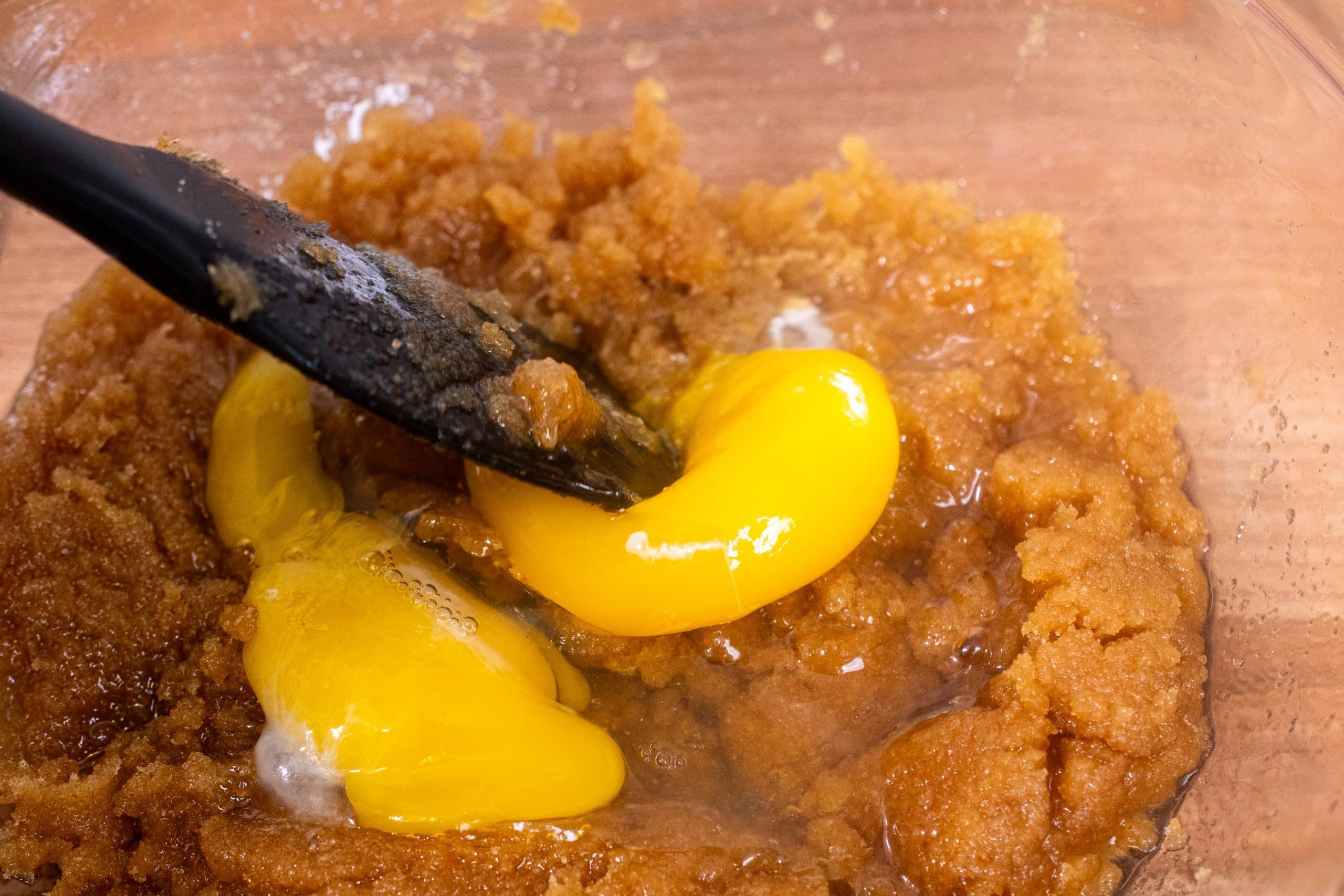 Brown sugar mixture with an egg being incorporated for cookie dough.