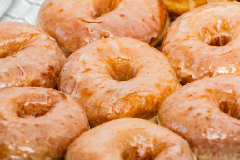 Fresh homemade glazed donuts with shiny vanilla glaze close up, soft fluffy yeast donuts with bakery-style crackly icing