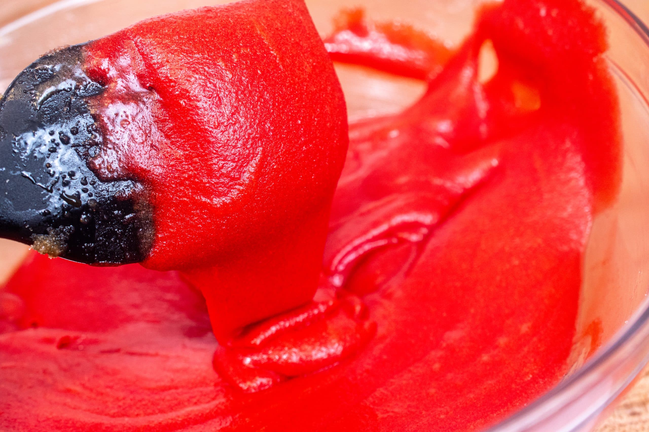 Smooth red-colored cookie dough being mixed in a bowl.
