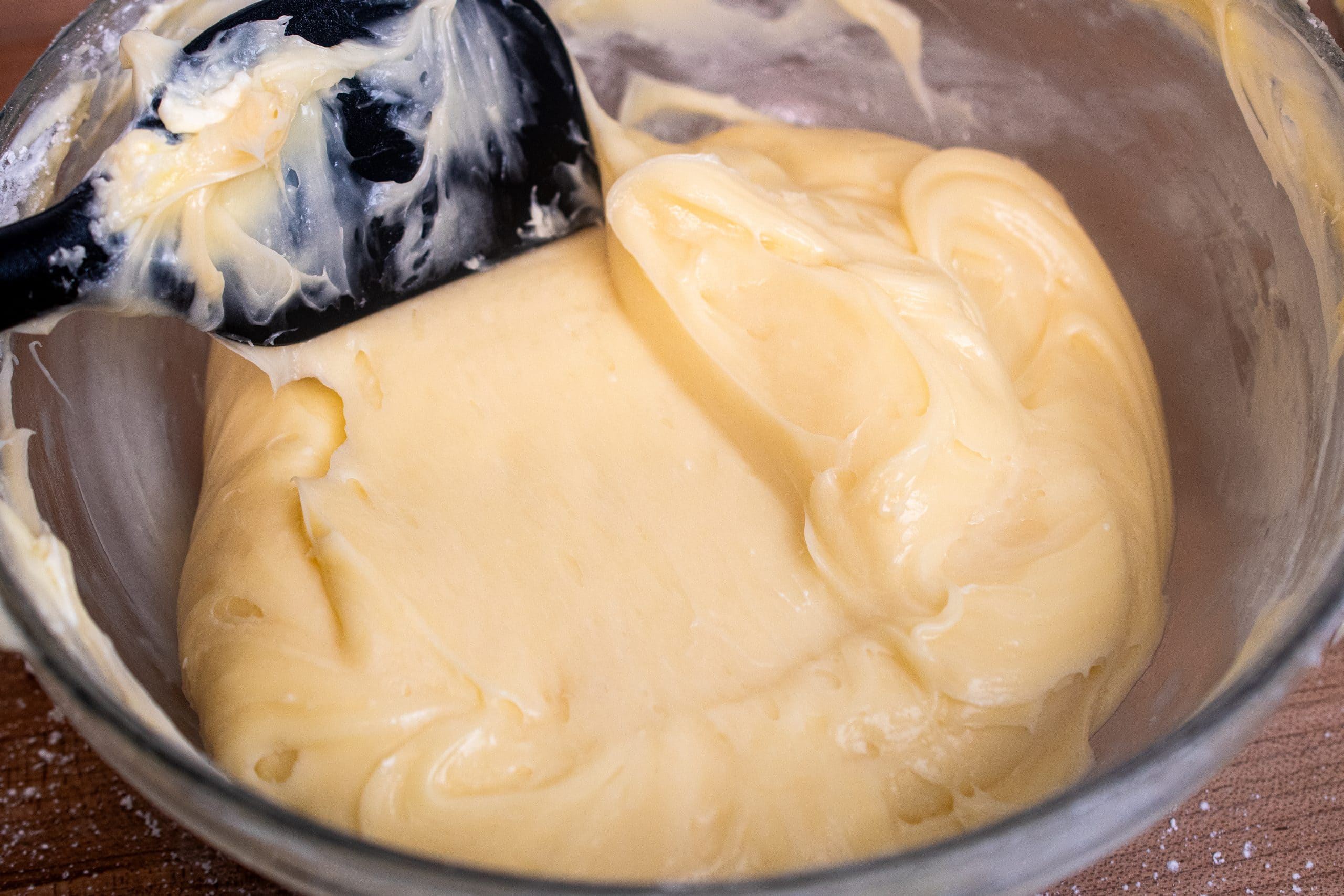 Piping cream cheese frosting onto red velvet cupcakes for a perfect smooth finish.