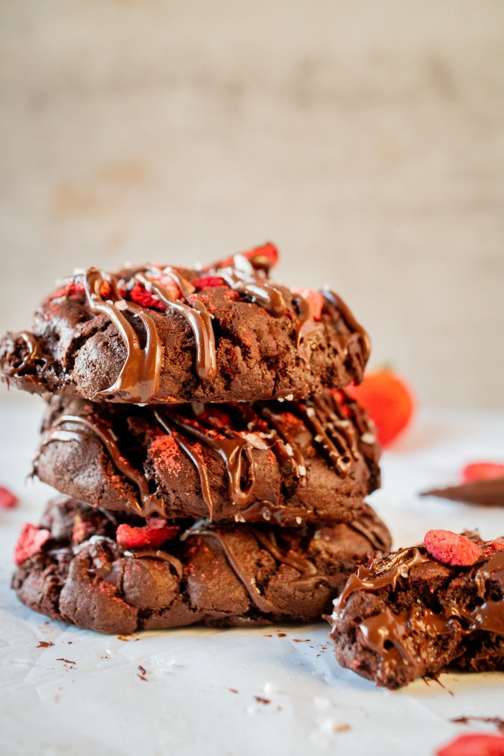 Stack of chocolate covered strawberry cookies with melty chocolate drizzle and red strawberry pieces.