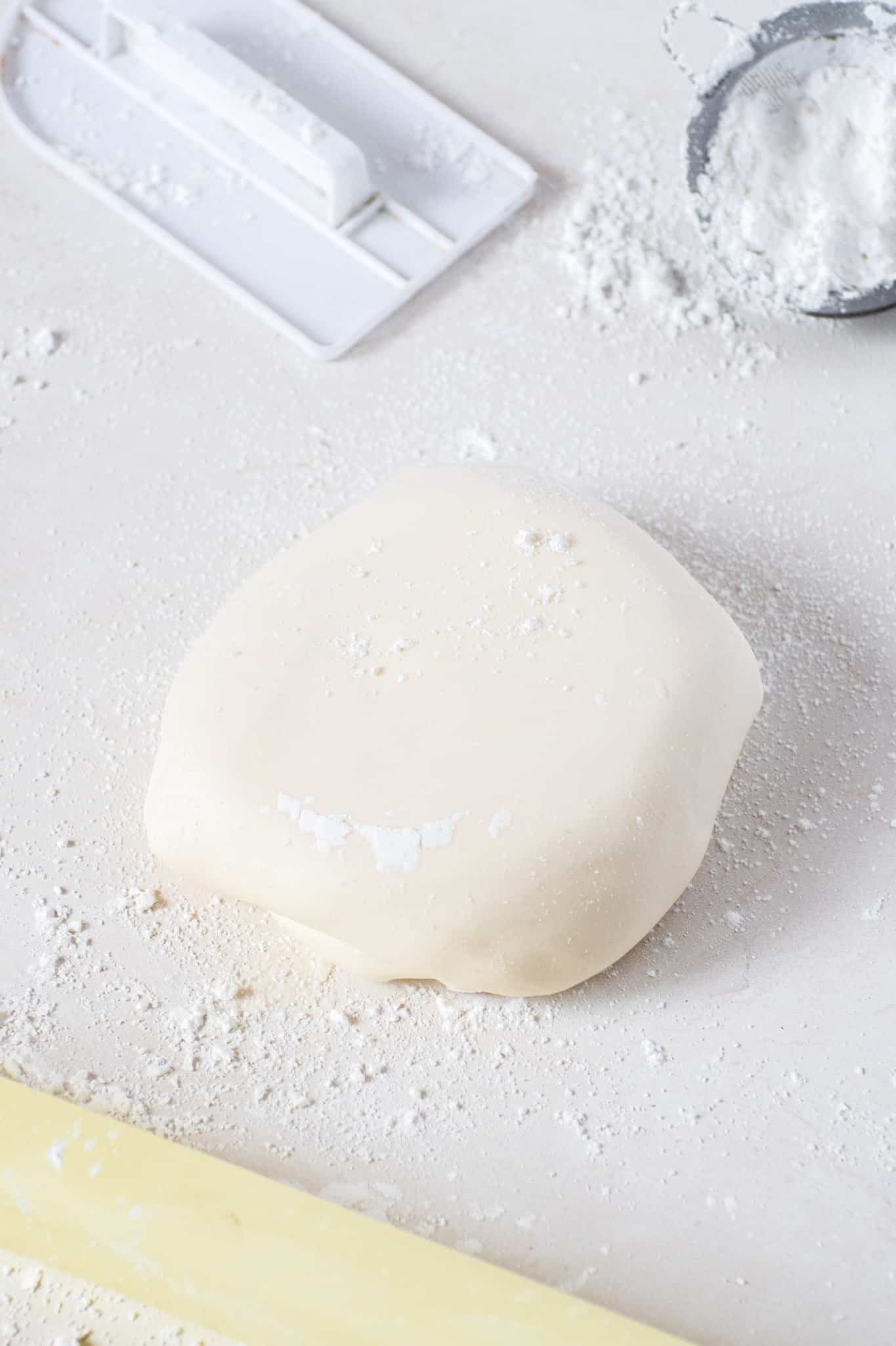 Homemade marshmallow fondant dough on a floured surface ready to roll