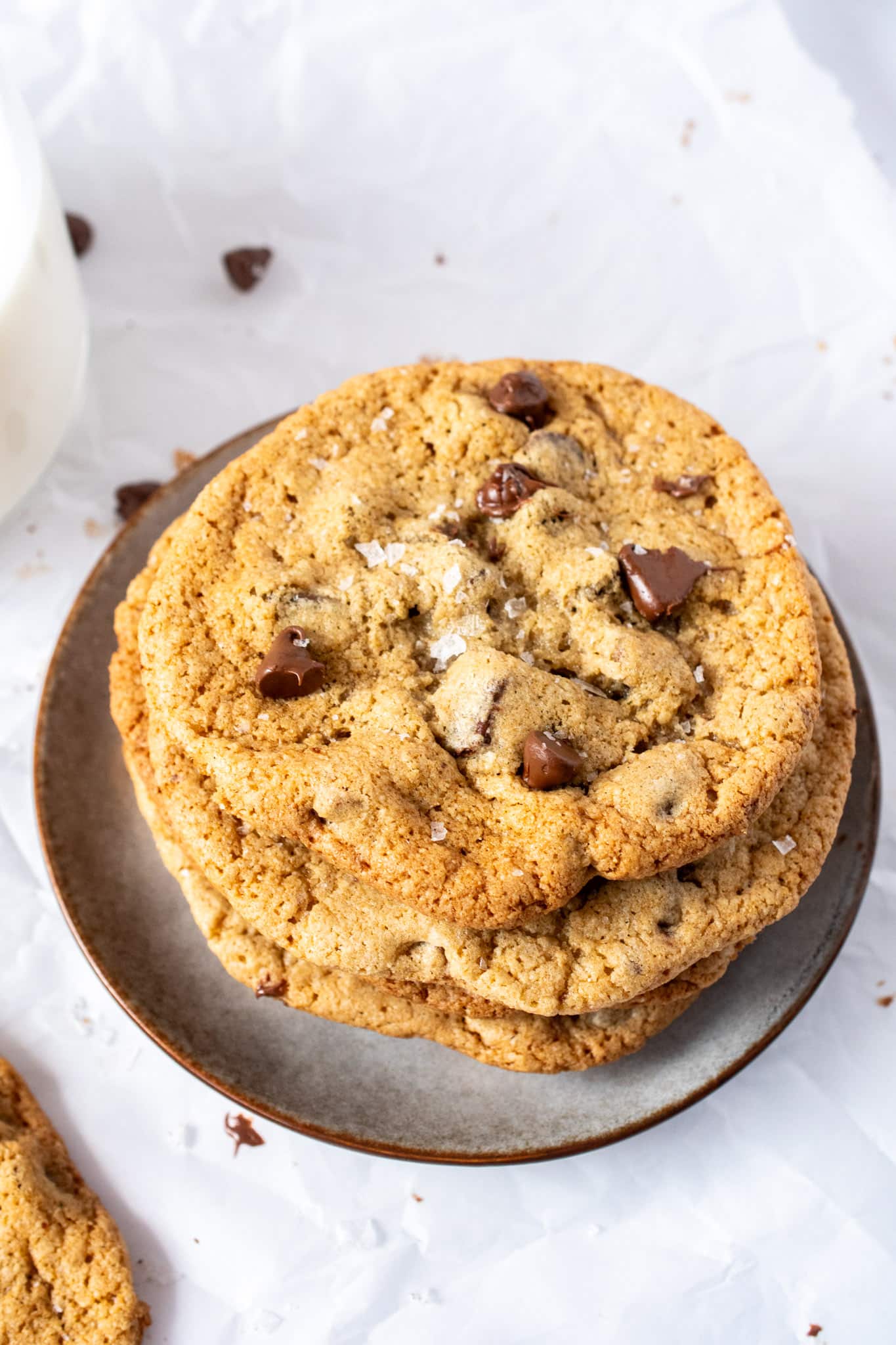 Stack of gluten free chocolate chip cookies with crisp golden edges, chewy centers, melty chocolate chunks, and flaky sea salt on a plate