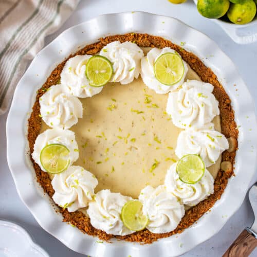 Easy homemade Key Lime Pie topped with whipped cream and fresh lime slices in a graham cracker crust.