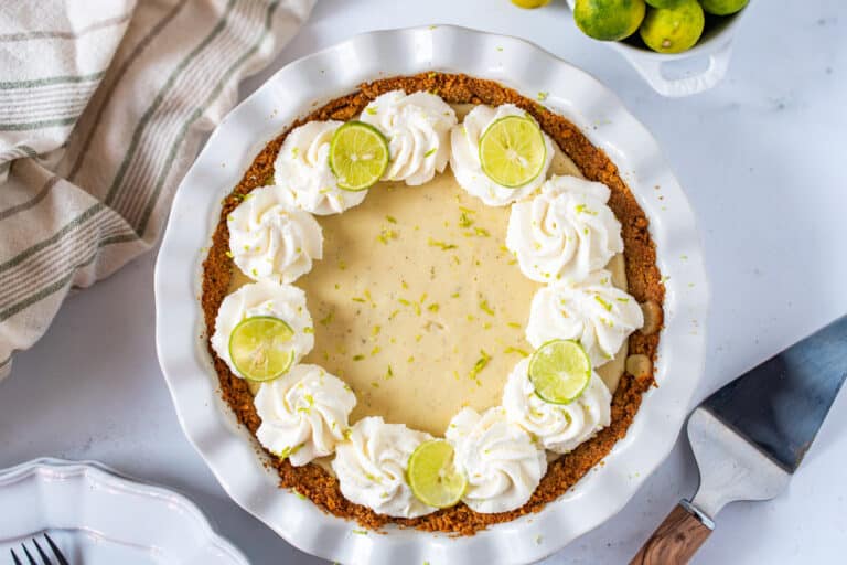 Easy homemade Key Lime Pie topped with whipped cream and fresh lime slices in a graham cracker crust.