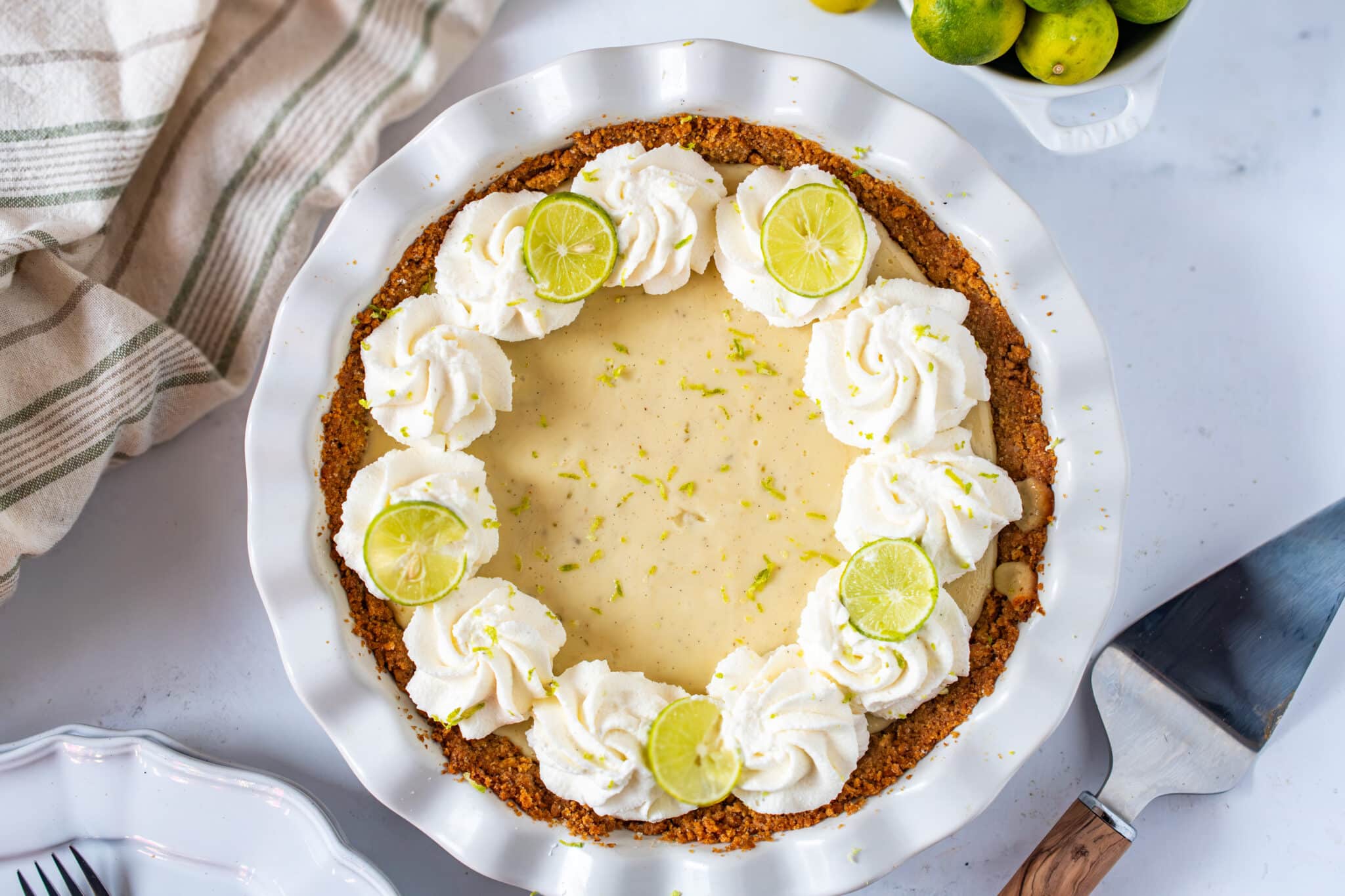 Easy homemade Key Lime Pie topped with whipped cream and fresh lime slices in a graham cracker crust.