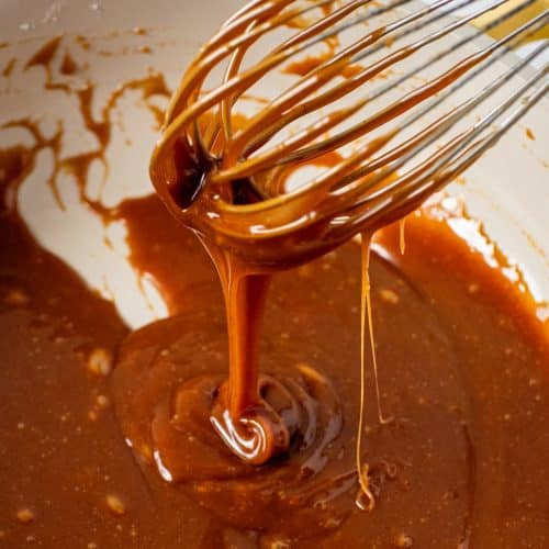 Close-up of whisk coated in homemade salted caramel sauce with glossy texture