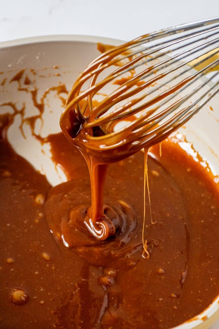 Close-up of whisk coated in homemade salted caramel sauce with glossy texture