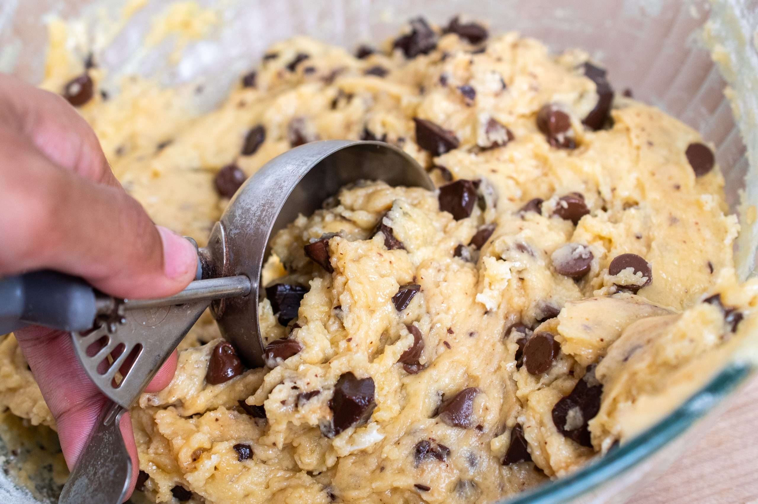 Scooping batter into a baking pan using a large cookie scoop.