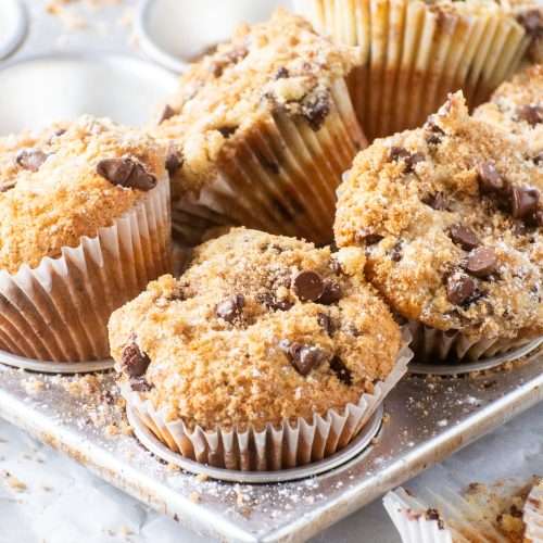 Bakery-Style Chocolate Chip Muffins with a crunchy top freshly baked in a silver tray.