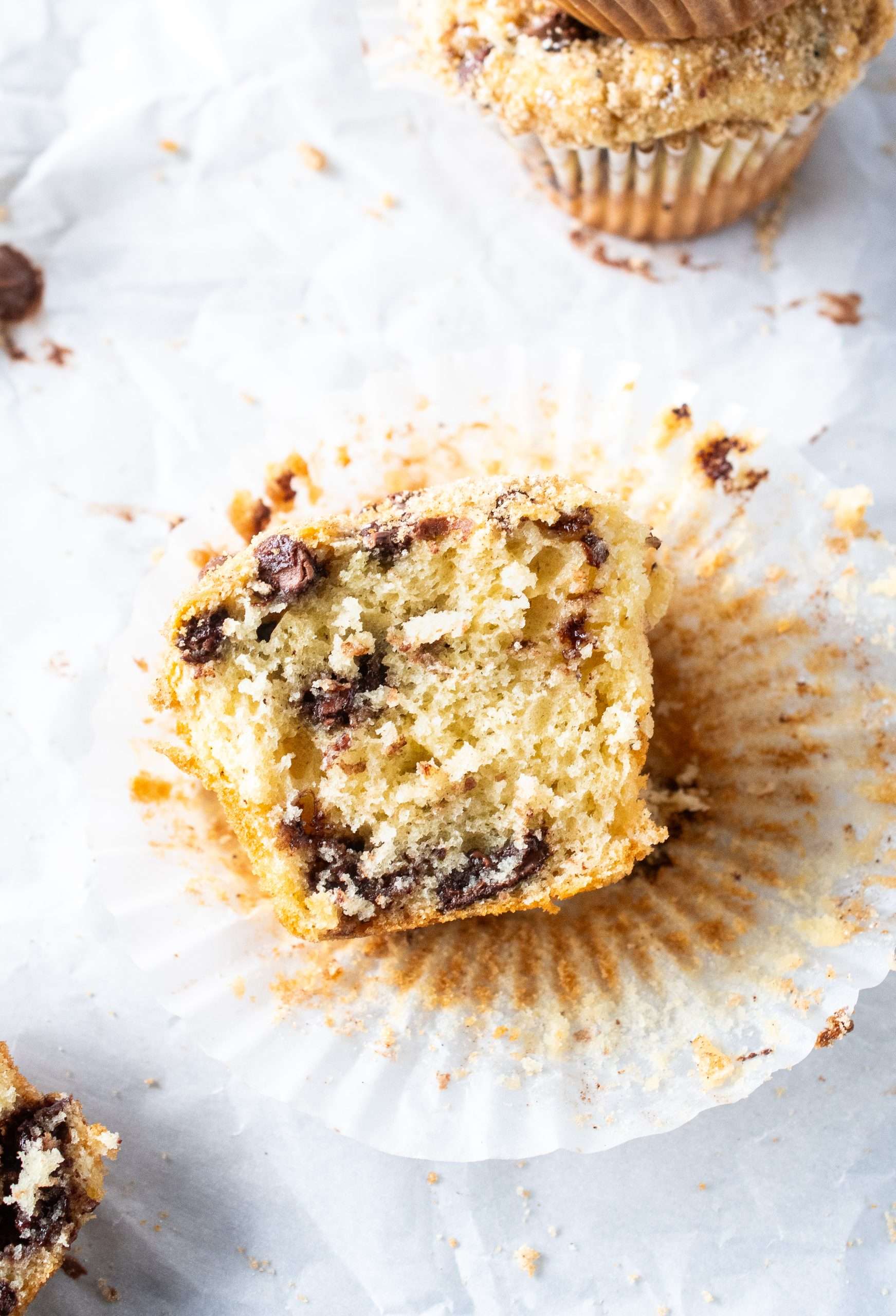 Half-eaten chocolate chip muffin showing a moist crumb and melted chocolate chips.