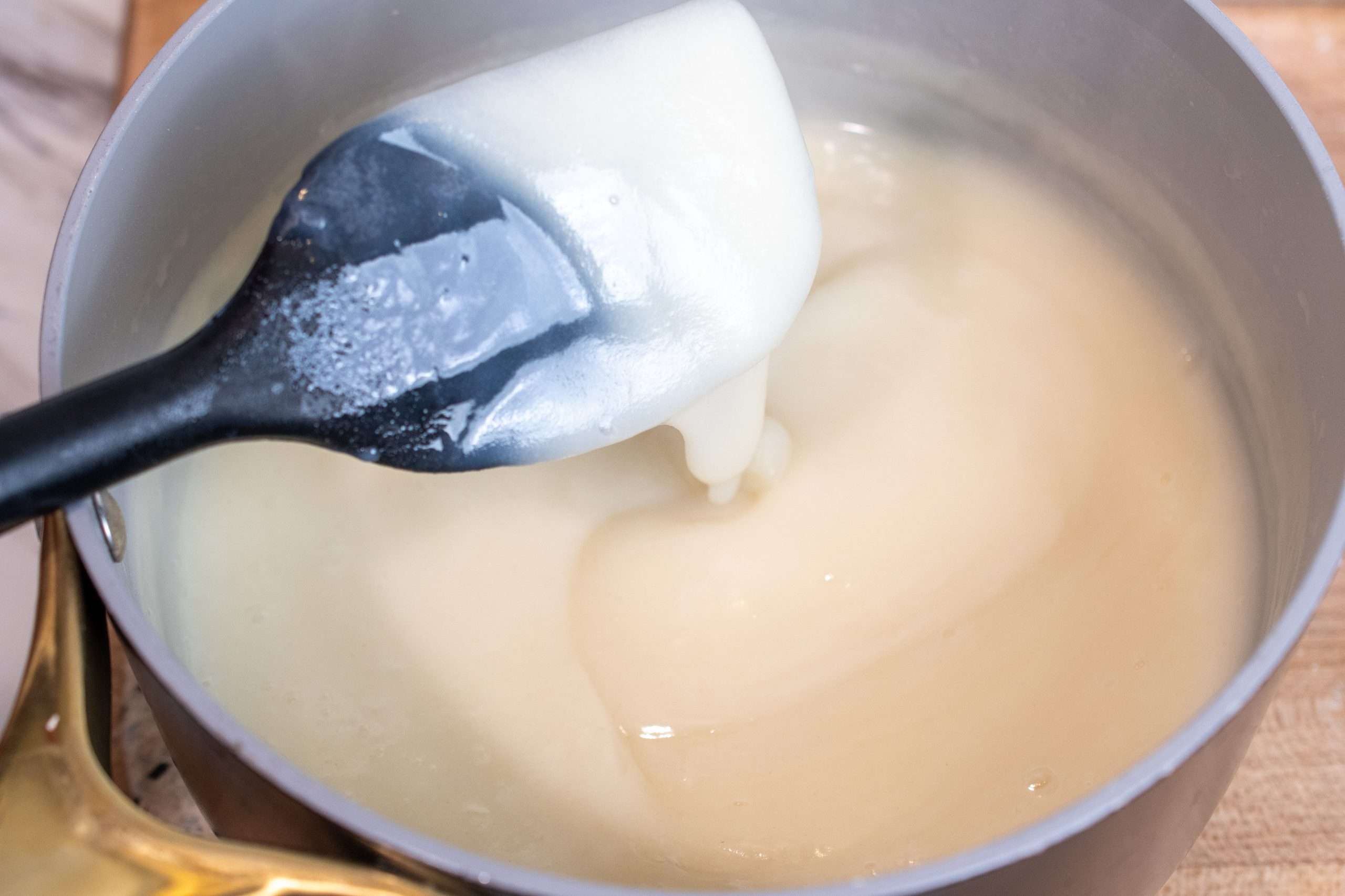 A black spatula showing the thick consistency of a roux after cooking.