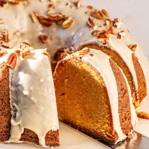 Close-up slices of Sweet Potato Pound Cake with maple glaze dripping down the sides and chopped pecans on top.