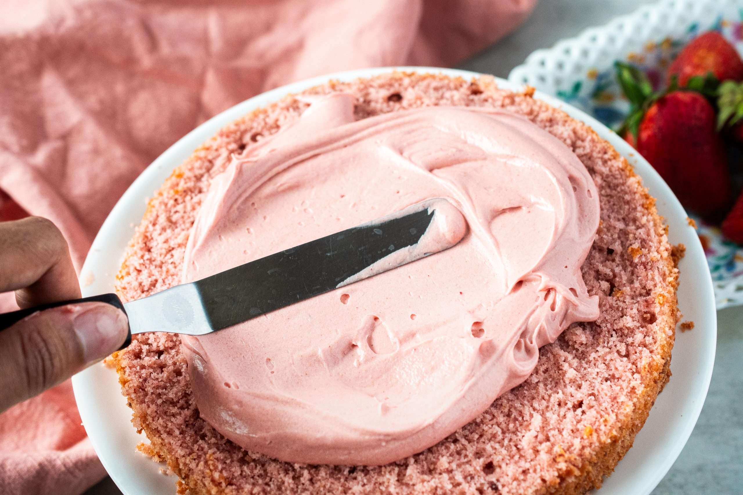 Spreading frosting onto cake until smooth.