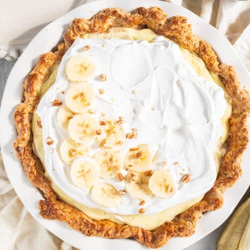Banana cream pie topped with whipped cream and sliced bananas.