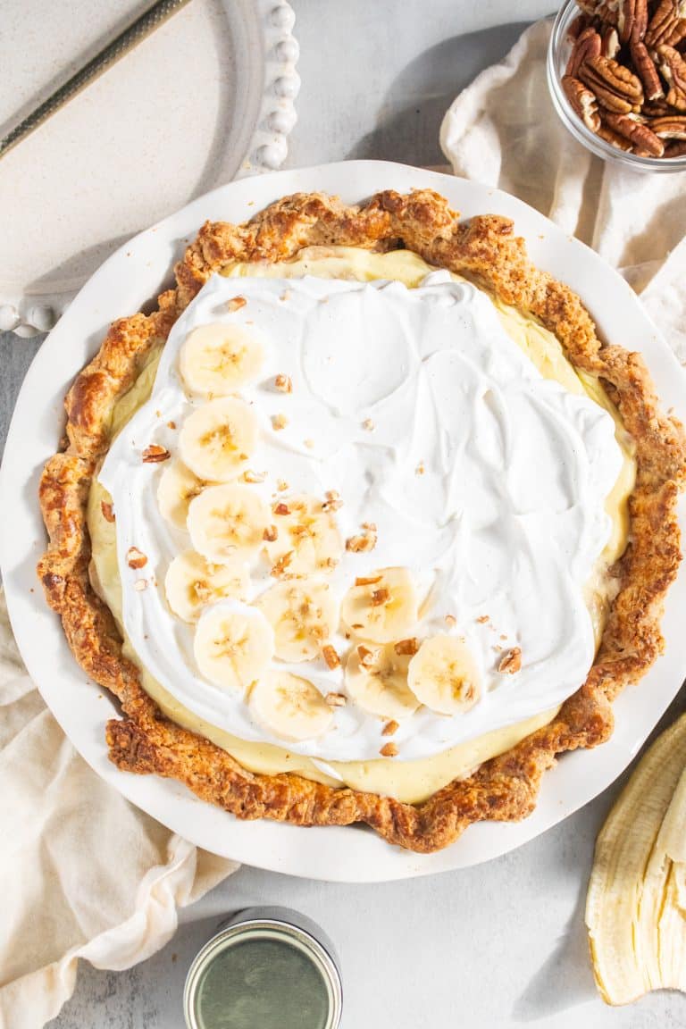 Banana cream pie topped with whipped cream and sliced bananas.