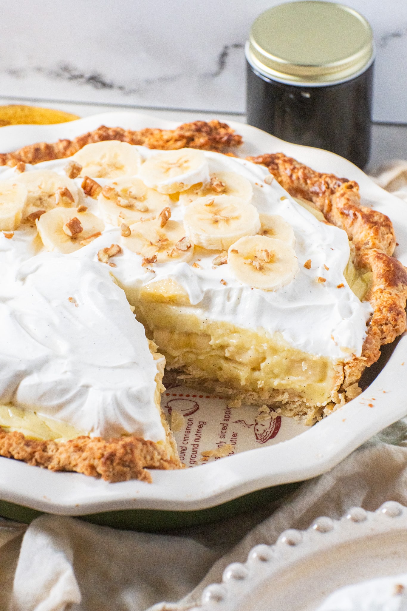 Slice of banana cream pie with silky custard, fresh banana slices, whipped cream topping, and a flaky buttery crust.