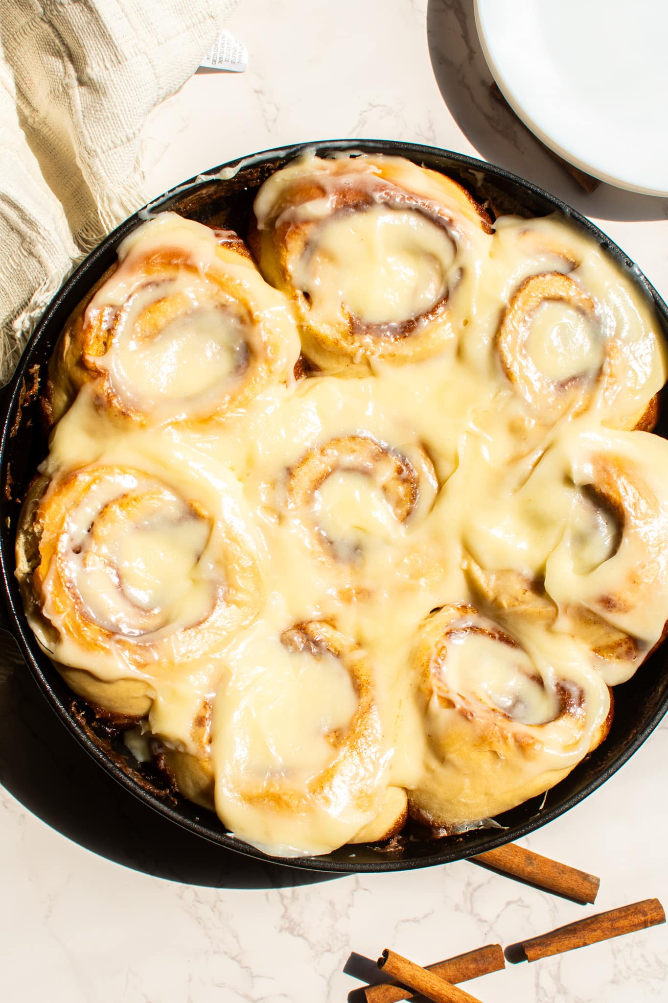 Freshly baked gooey cinnamon rolls in a cast iron skillet topped with cream cheese frosting