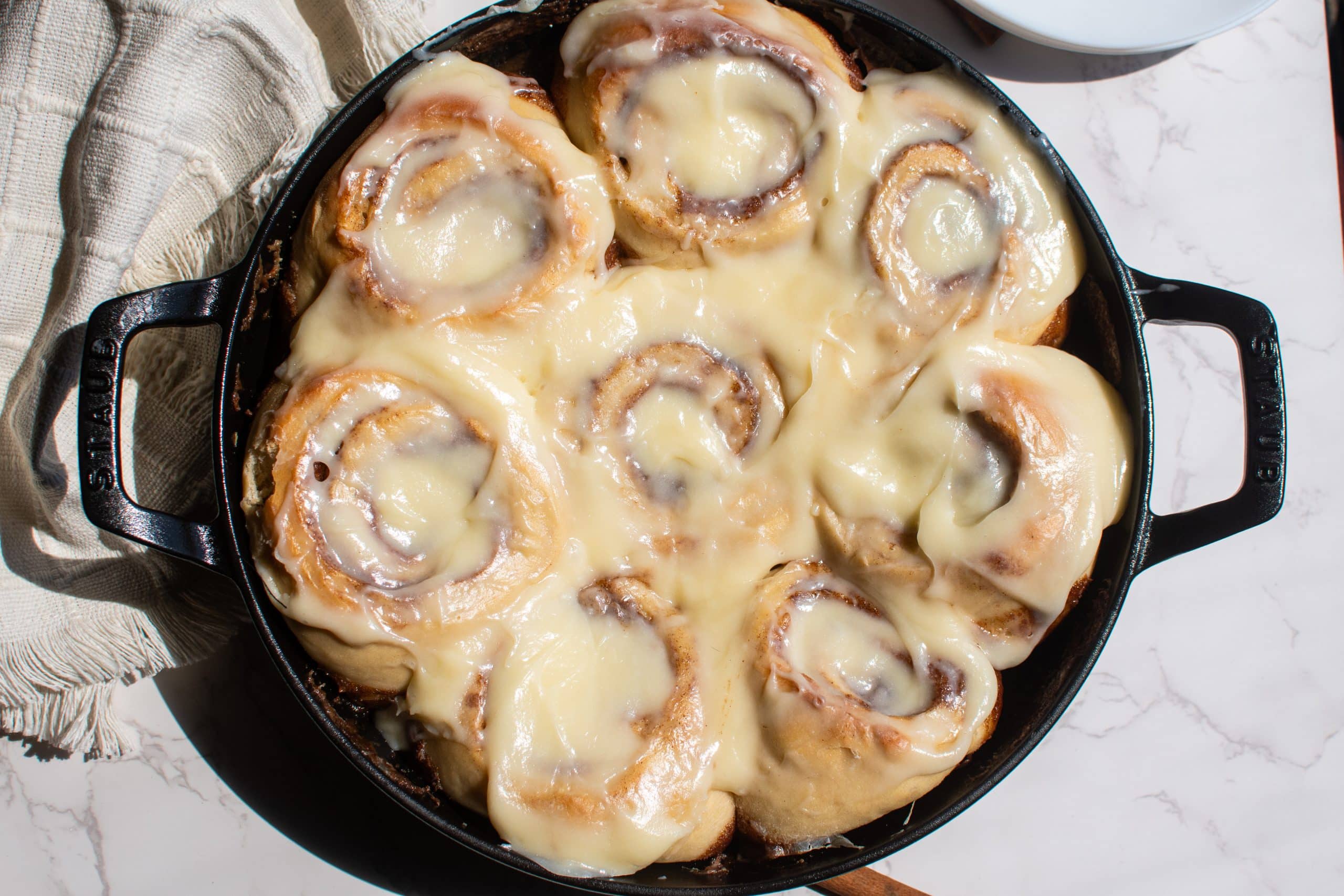 Freshly baked make-ahead cinnamon rolls in a cast iron skillet topped with creamy glaze.