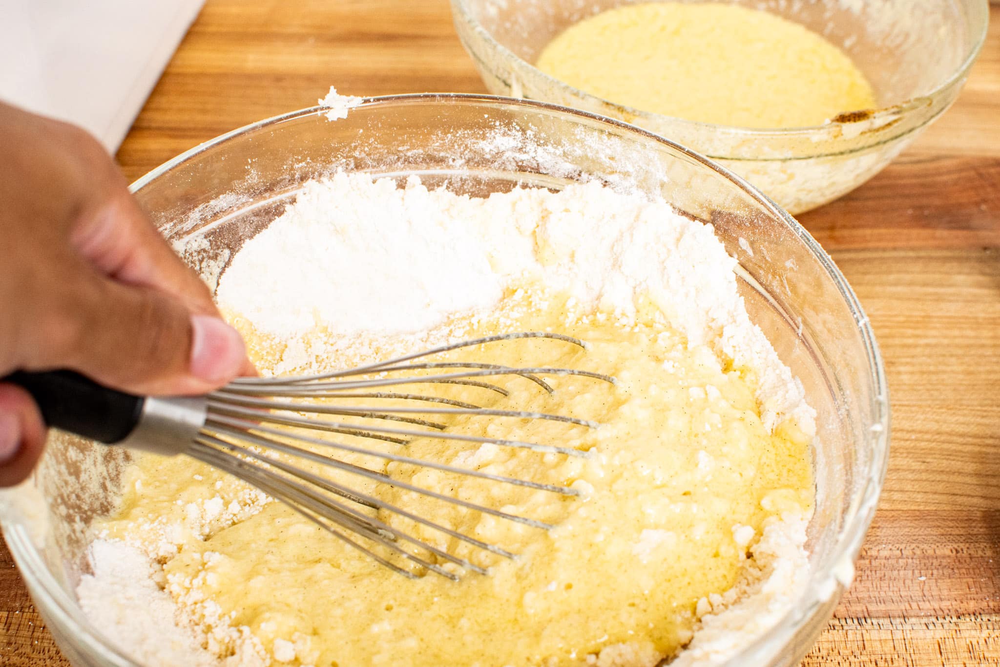 Whisking the wet ingredients with the dry to create a smooth cake batter.