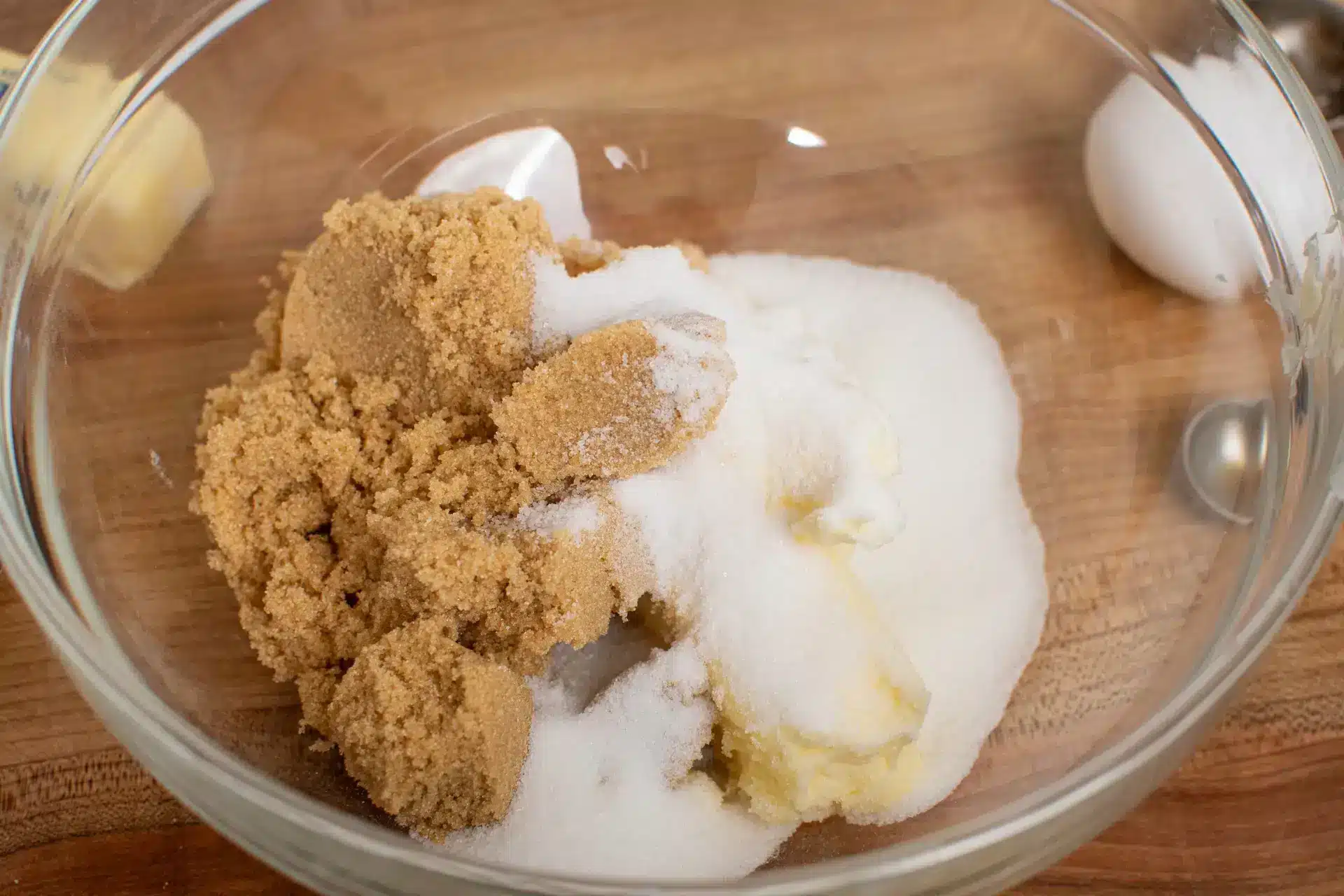 Brown sugar and white sugar added to softened butter in a mixing bowl.
