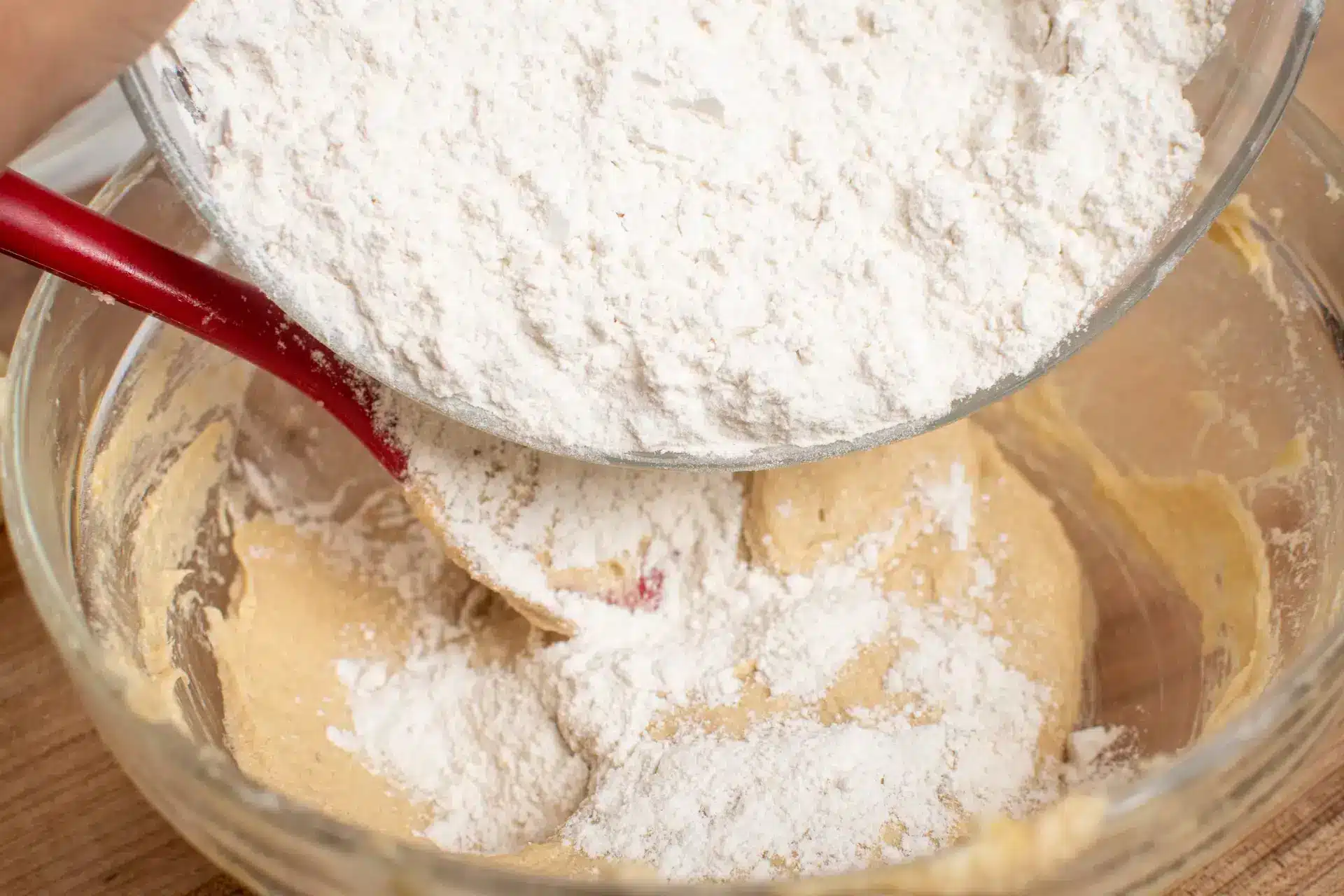 Flour being added to cookie dough in a mixing bowl.