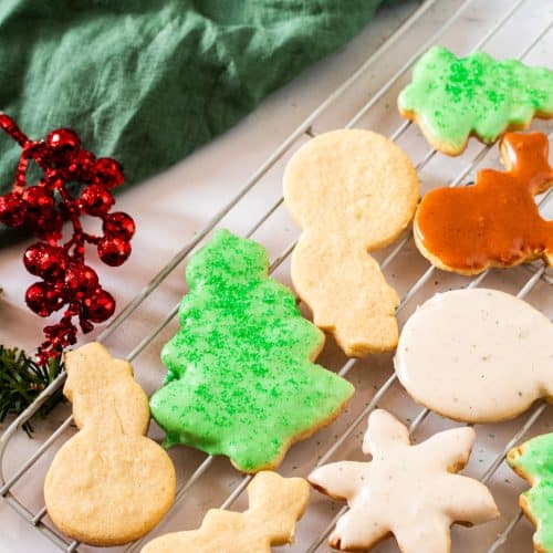 Decorated sugar cookie cut outs cooling on a rack — buttery, soft sugar cookies that hold their shape and are perfect for icing during the holidays.