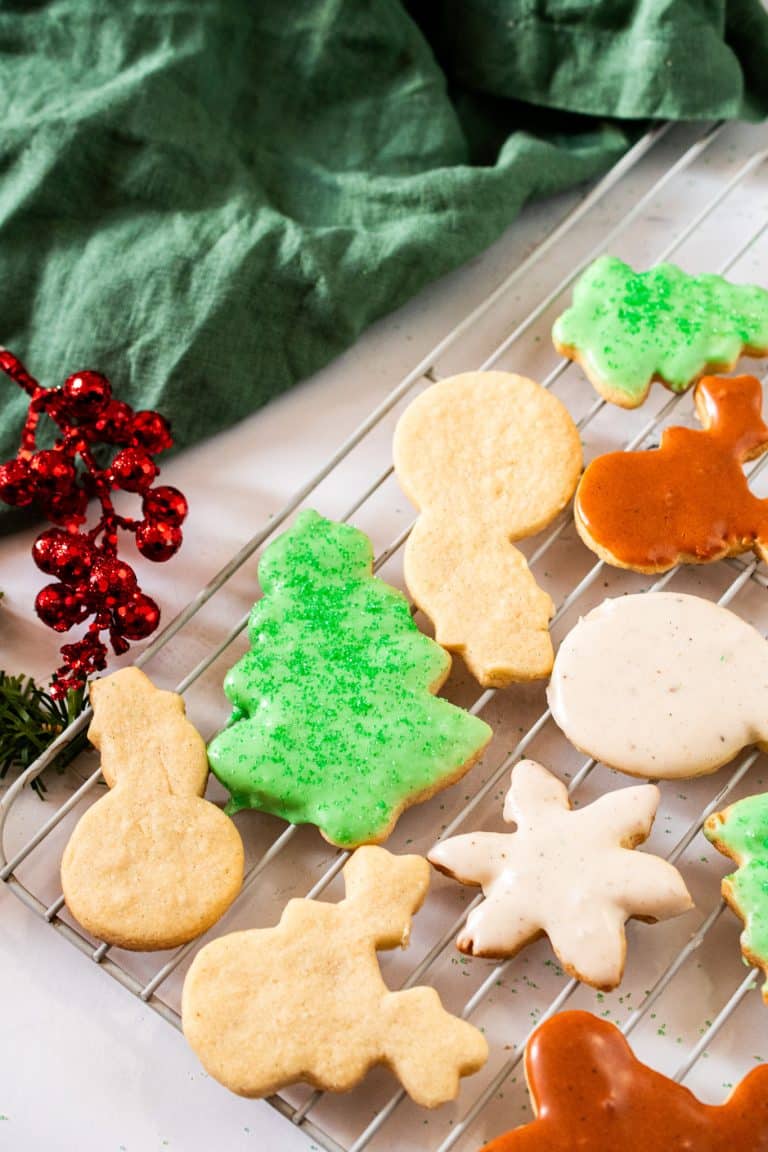 Decorated sugar cookie cut outs cooling on a rack — buttery, soft sugar cookies that hold their shape and are perfect for icing during the holidays.