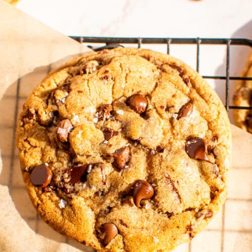 Large chewy chocolate chip cookie cooling on a wire rack with melted chocolate chips