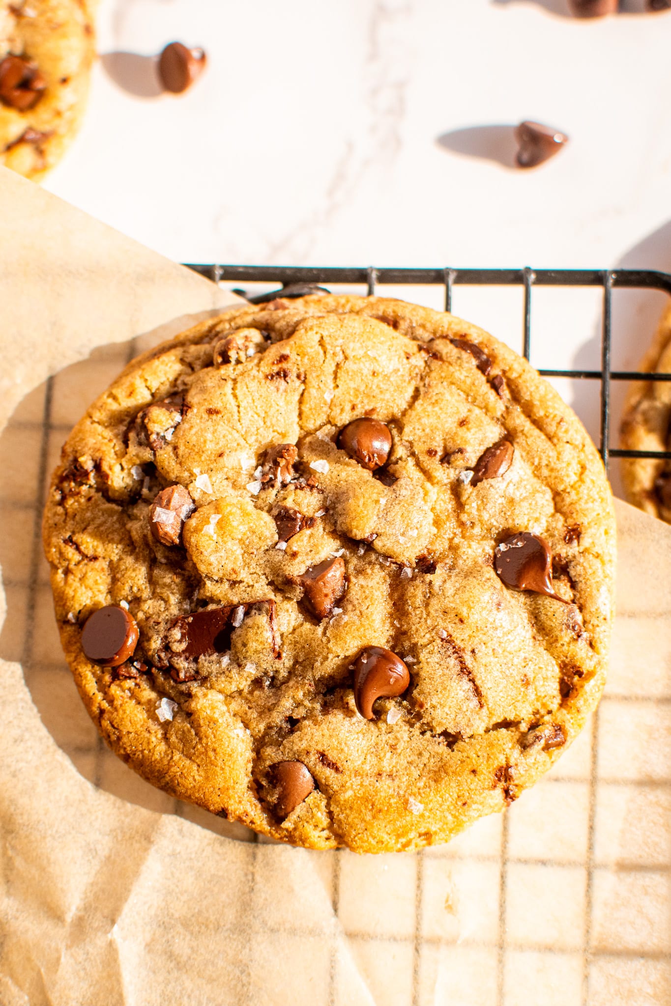 Large chewy chocolate chip cookie cooling on a wire rack with melted chocolate chips