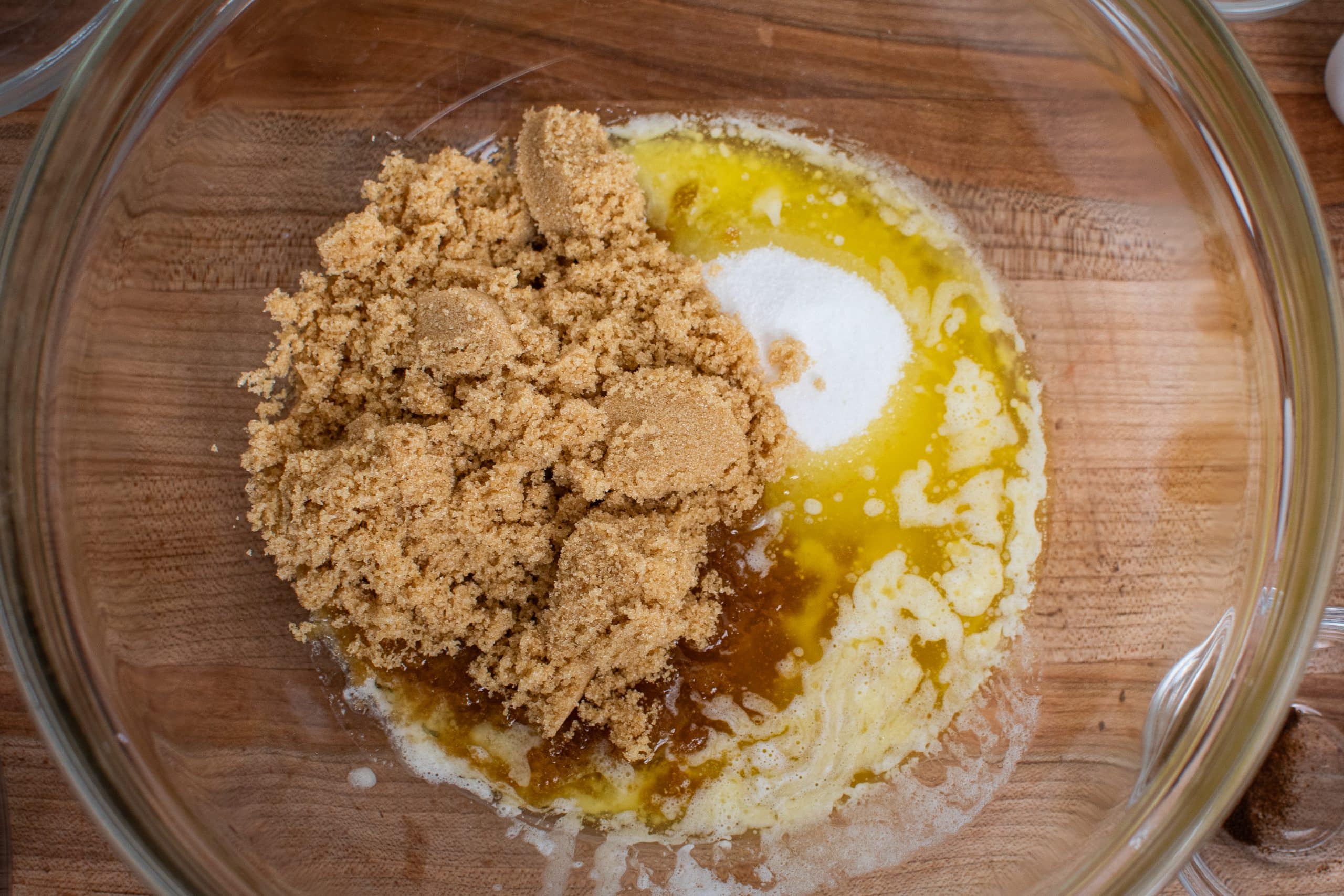 Melted butter and brown sugar in a glass bowl together for double chocolate chip cookies.