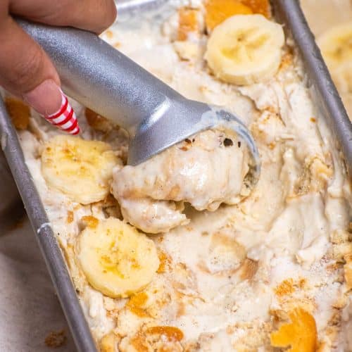 Scooping banana pudding ice cream with banana slices and crushed vanilla wafers in a loaf pan