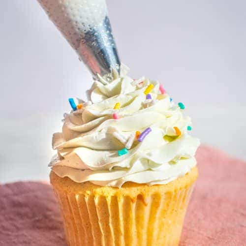 Vanilla cupcake topped with smooth buttercream frosting and colorful sprinkles.