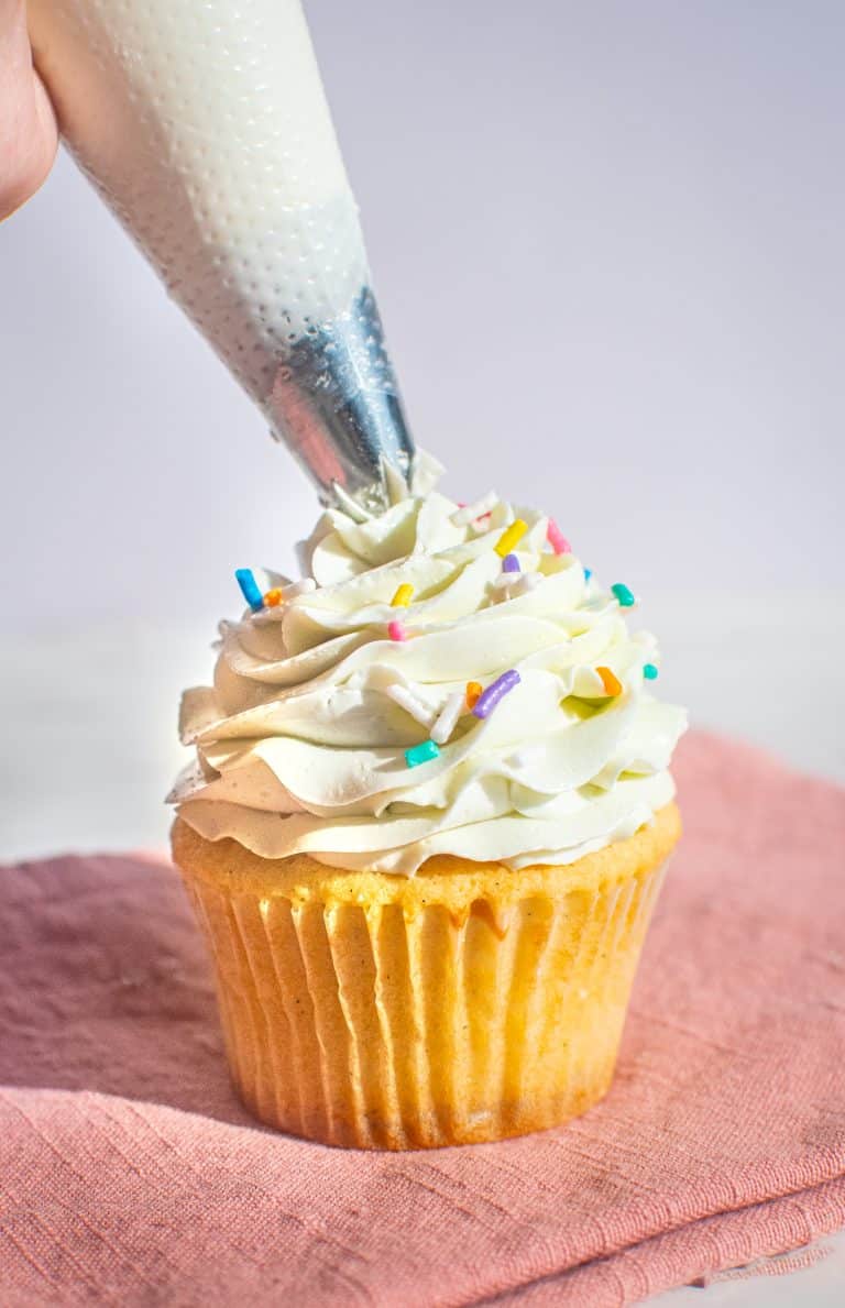 Vanilla cupcake topped with smooth buttercream frosting and colorful sprinkles.