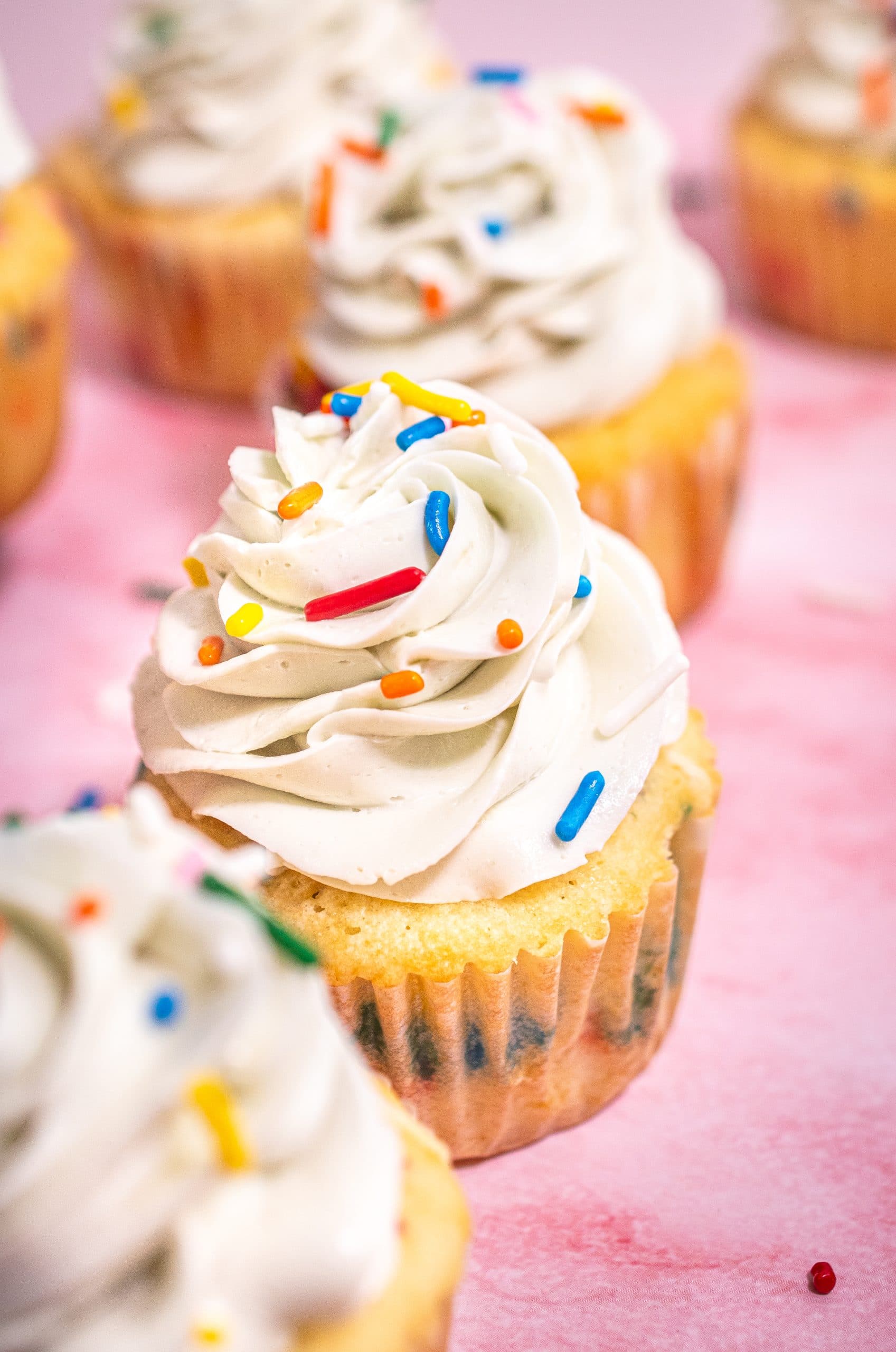 Close-up of a single Funfetti cupcake with a swirl of vanilla buttercream frosting and colorful sprinkles on top.