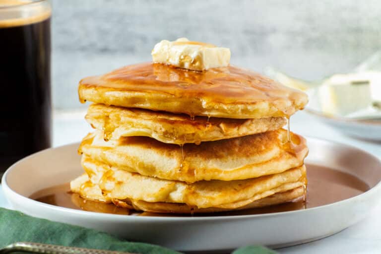 Crispy edge buttermilk pancakes stacked with melted butter and maple syrup, served warm
