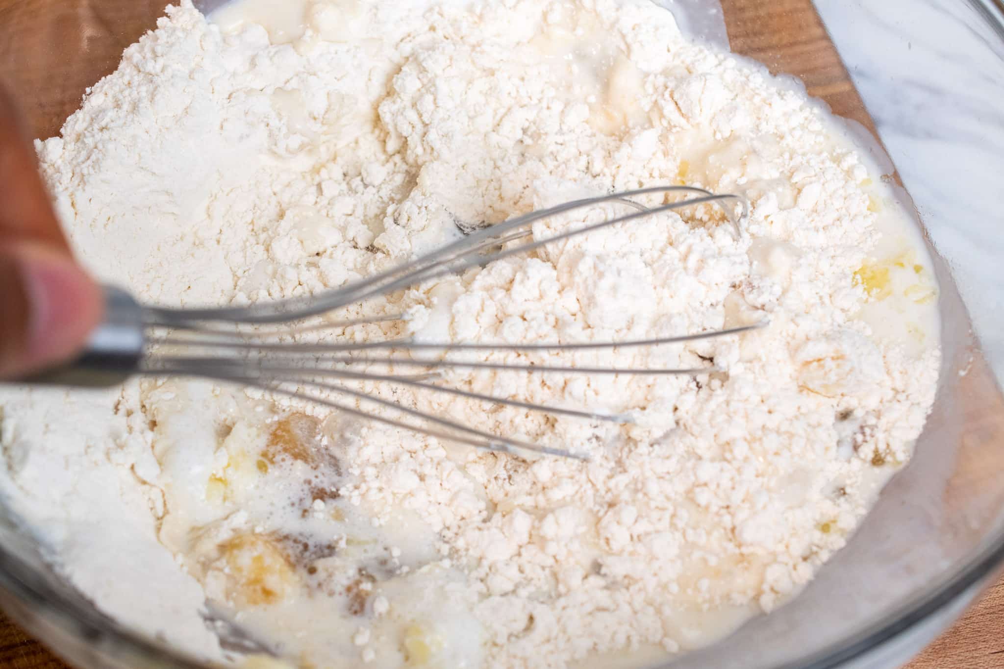 Mixing together flour, sugar, baking powder and salt before adding in milk.