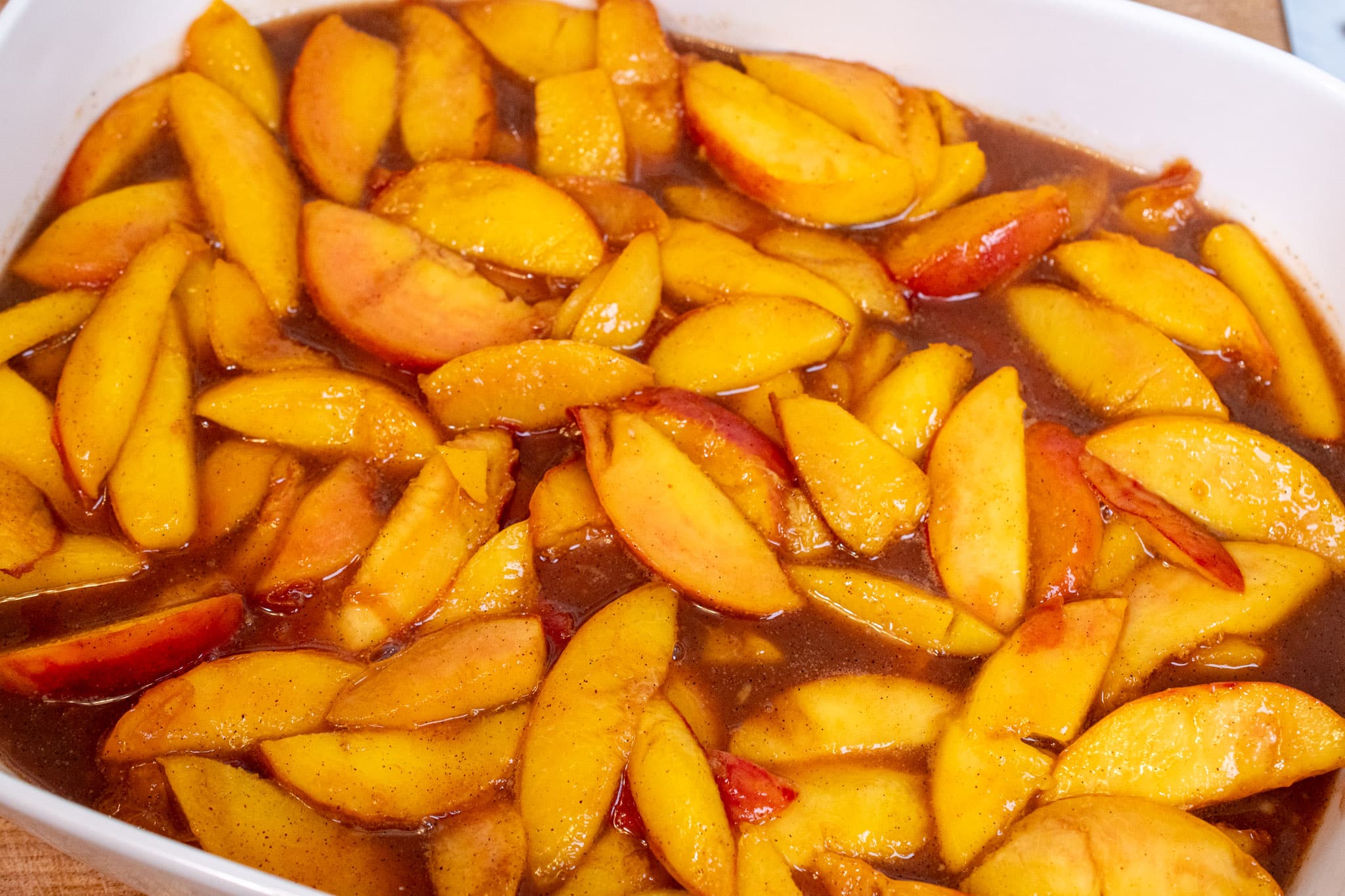 Adding the cooked peach filling to the baking dish