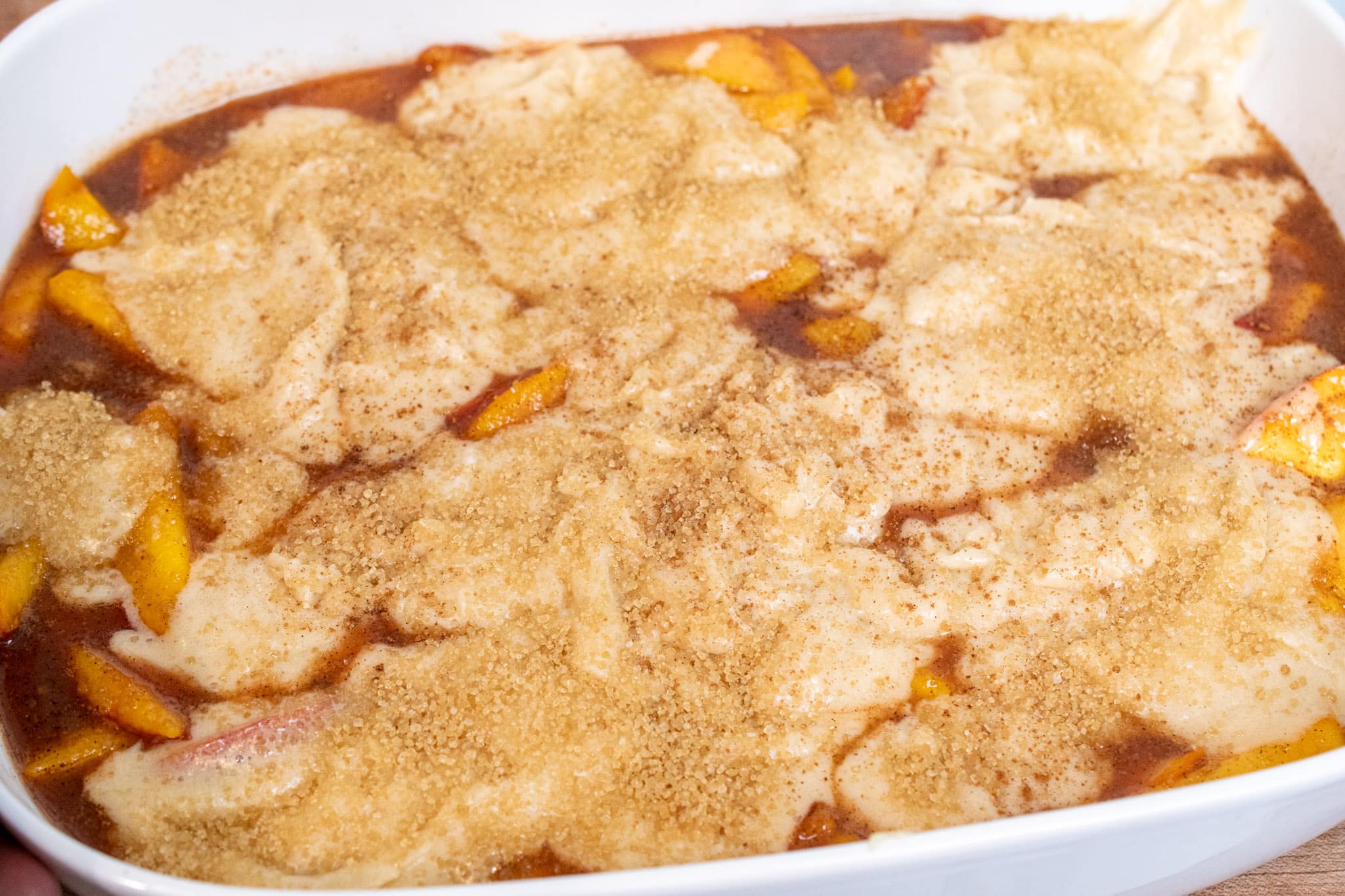 Peach filling topped with cobbler batter ready to be baked in the oven.