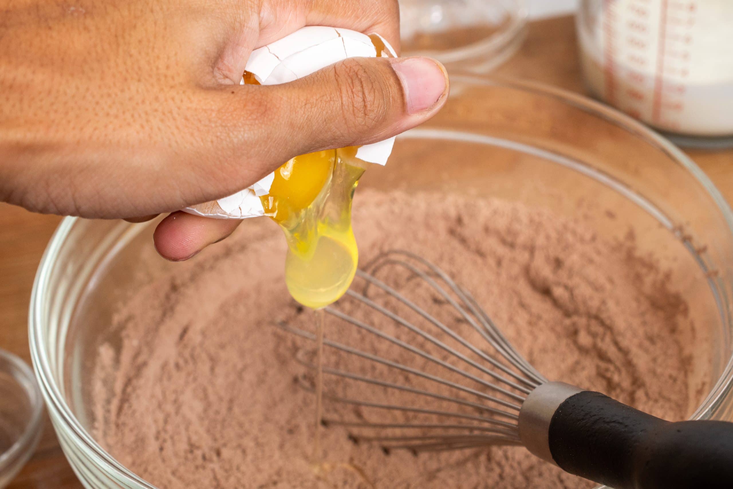 Cracking an egg into a bowl of cocoa powder and flour.