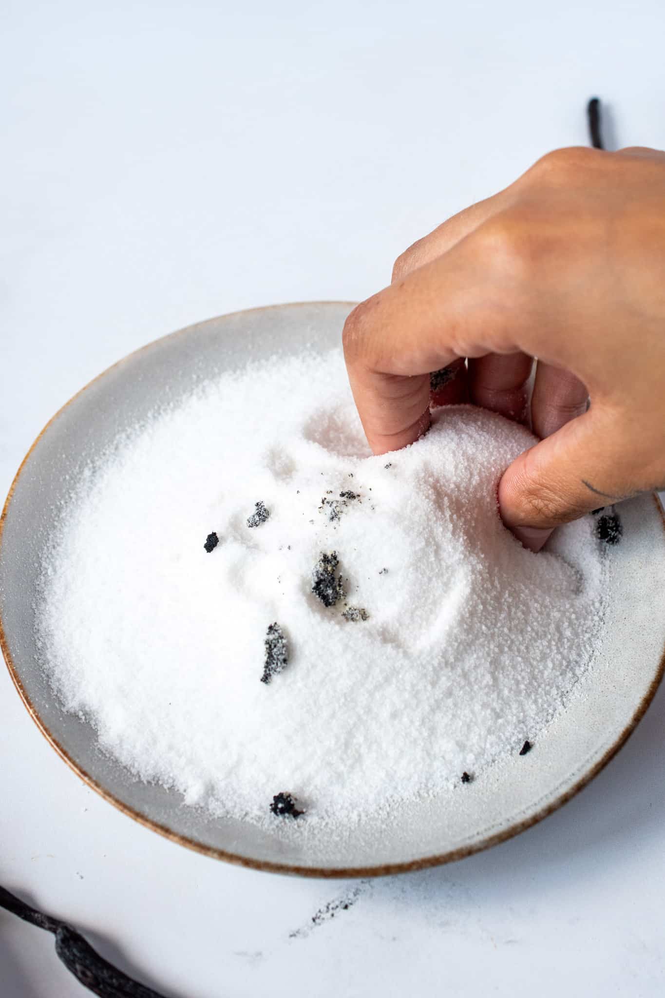 Pressing together vanilla seeds and sugar together to infuse the flavor.