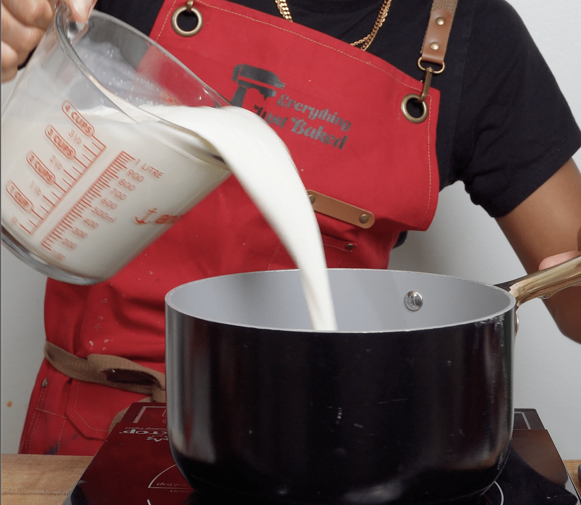Pouring heavy cream and milk inot a pot ready to be heated.