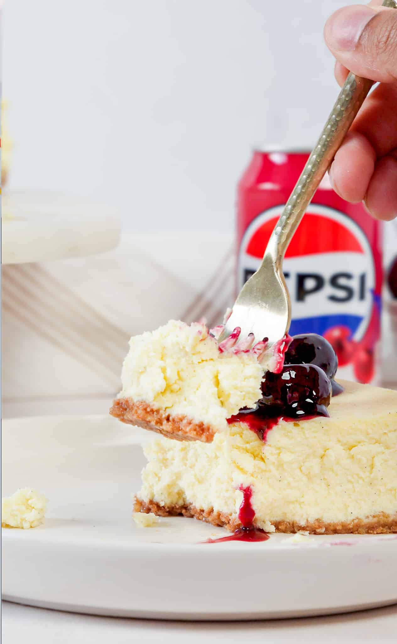 fork cutting into an ultra-creamy slice of cherry cheesecake with cherry compote