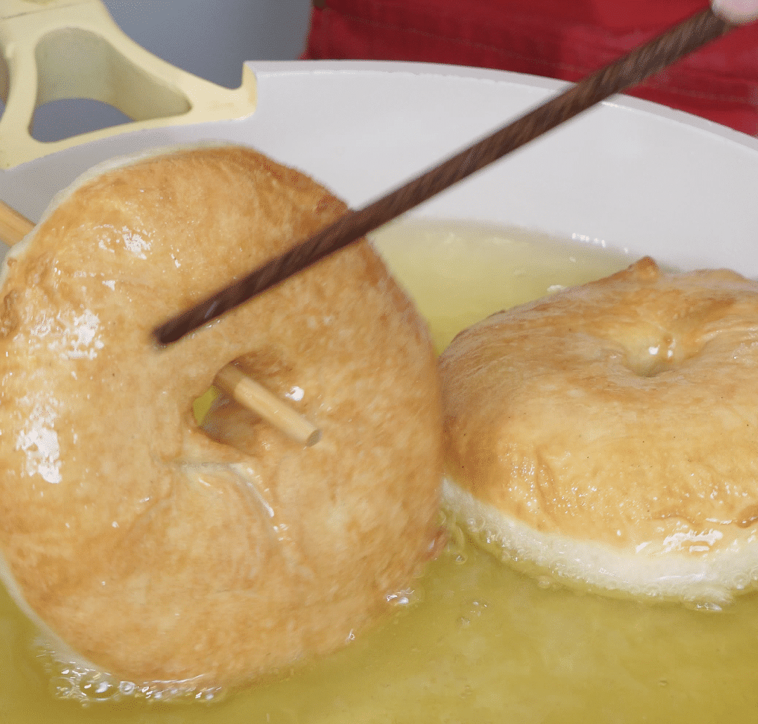 Frying donuts in hot oil using chopsticks.