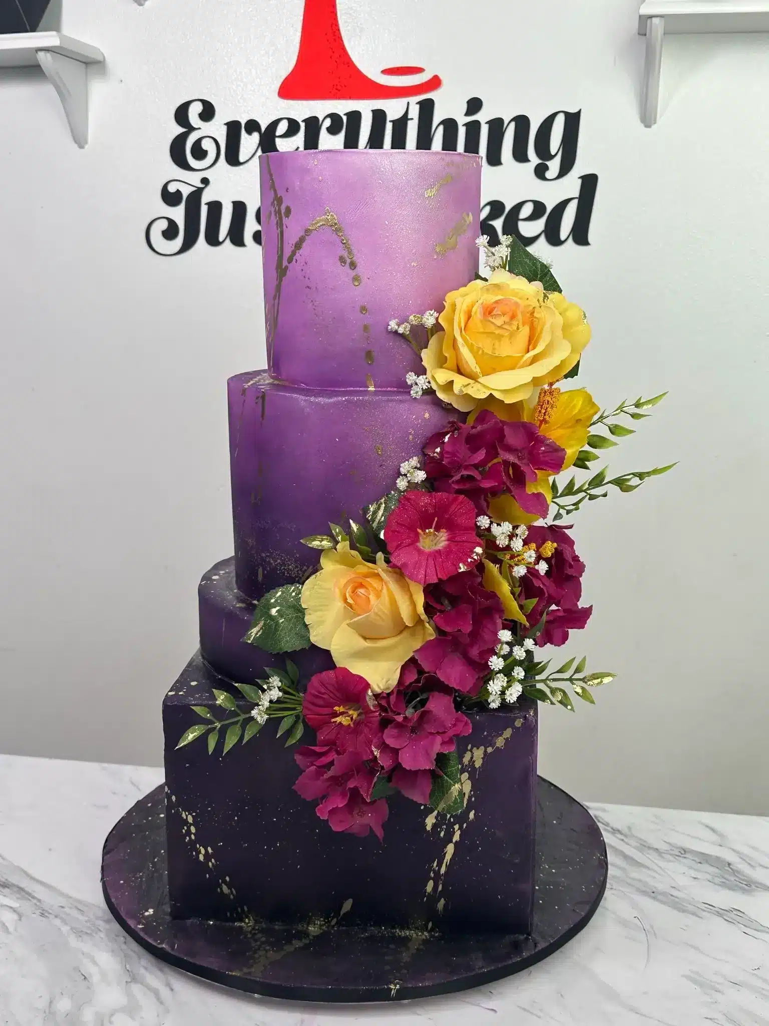 Purple tiered birthday cake with cascading flowers, perfect for birthdays or special occasions.
