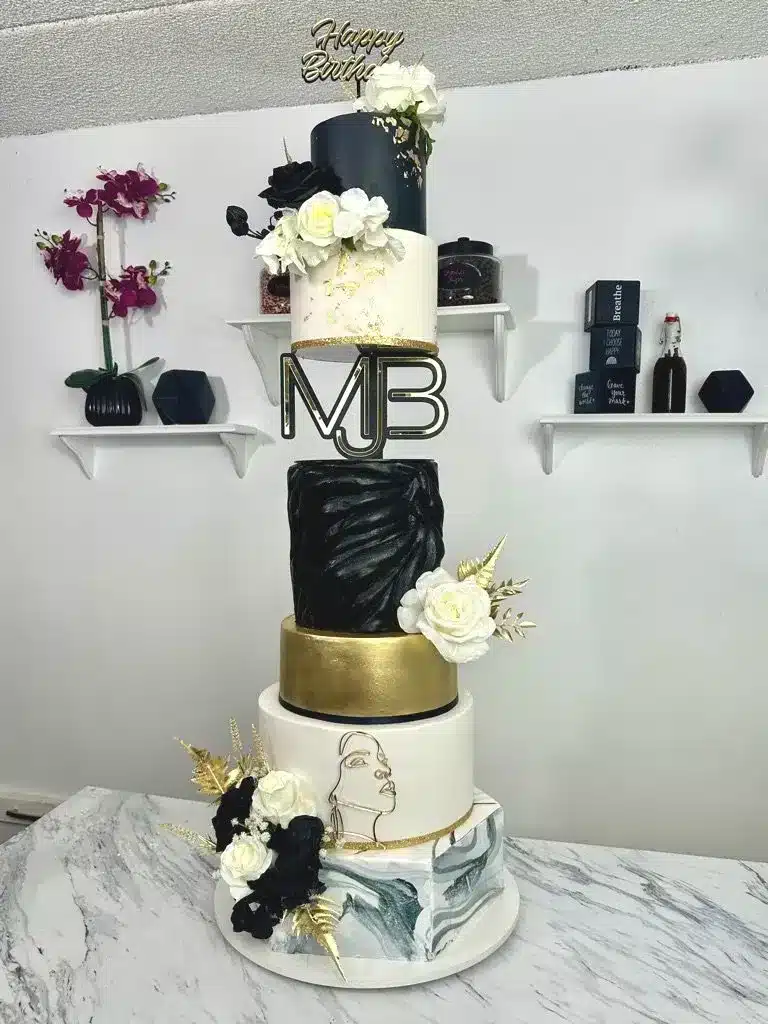 Wedding cake with chalkboard design, gold buttercream, and fresh floral decorations
