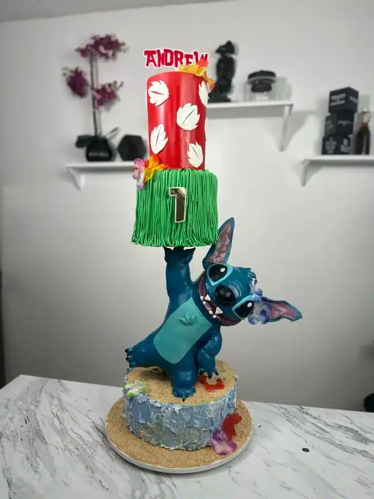 Lilo & Stitch birthday cake with red, green, and blue tiers, featuring beach details and a Stitch figure.